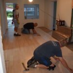 volunteers laying flooring inside a preservation and repair project